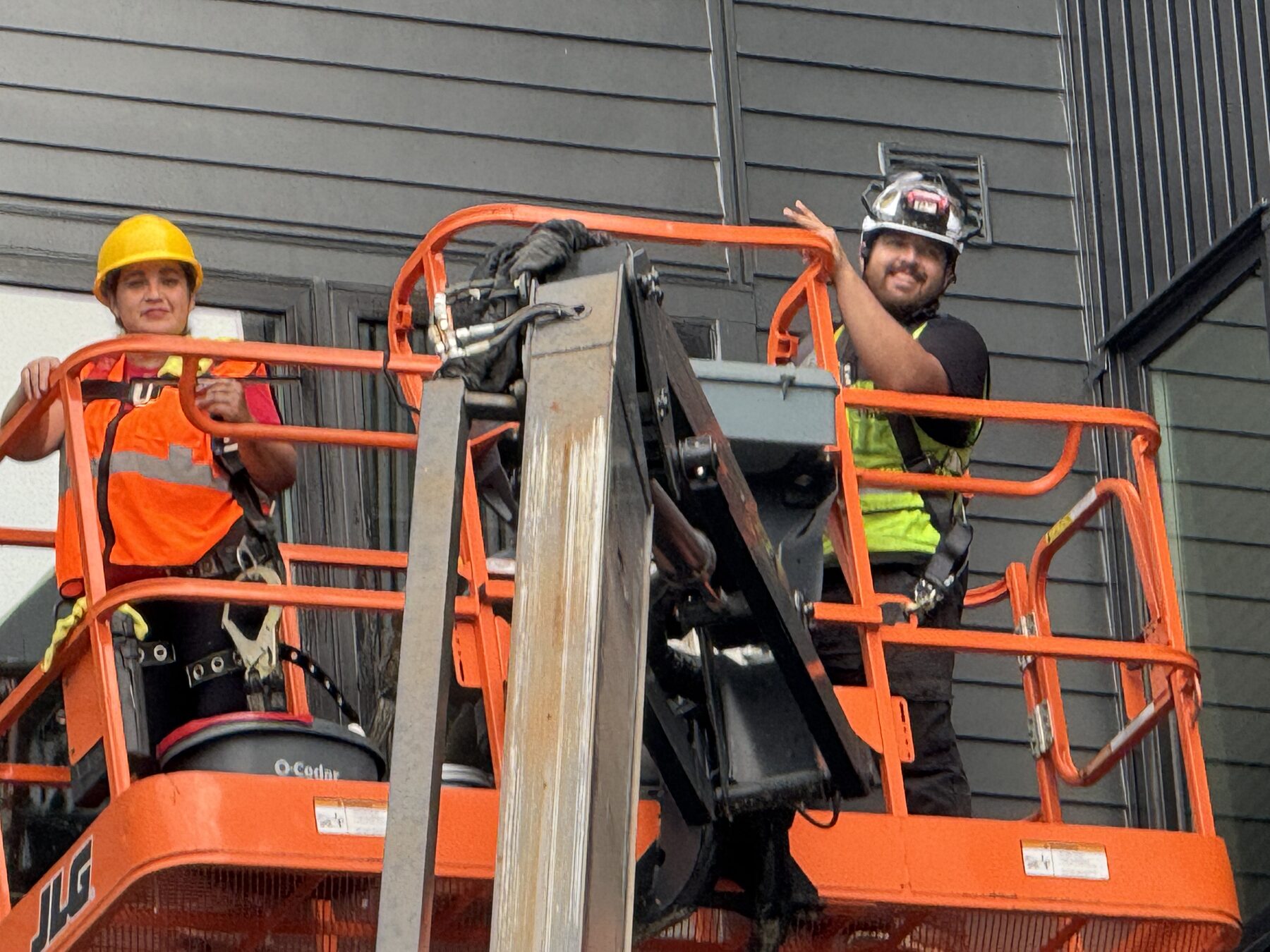 Two Santa Cruz Cleaning team members in a lift bucket cleaning the exterior of a building